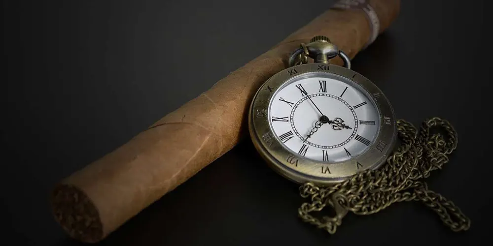 Zigarre mit einer danebenliegenden Sackuhr